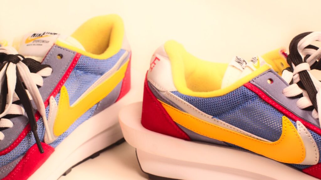 A pair of sneakers with a yellow, blue, and red shoelace