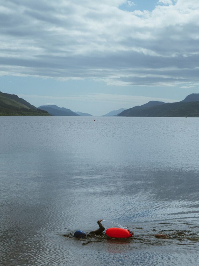 Red buoy on a calm loch with distant mountains.
