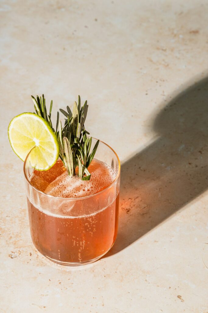 cocktail with lime and rosemary garnish