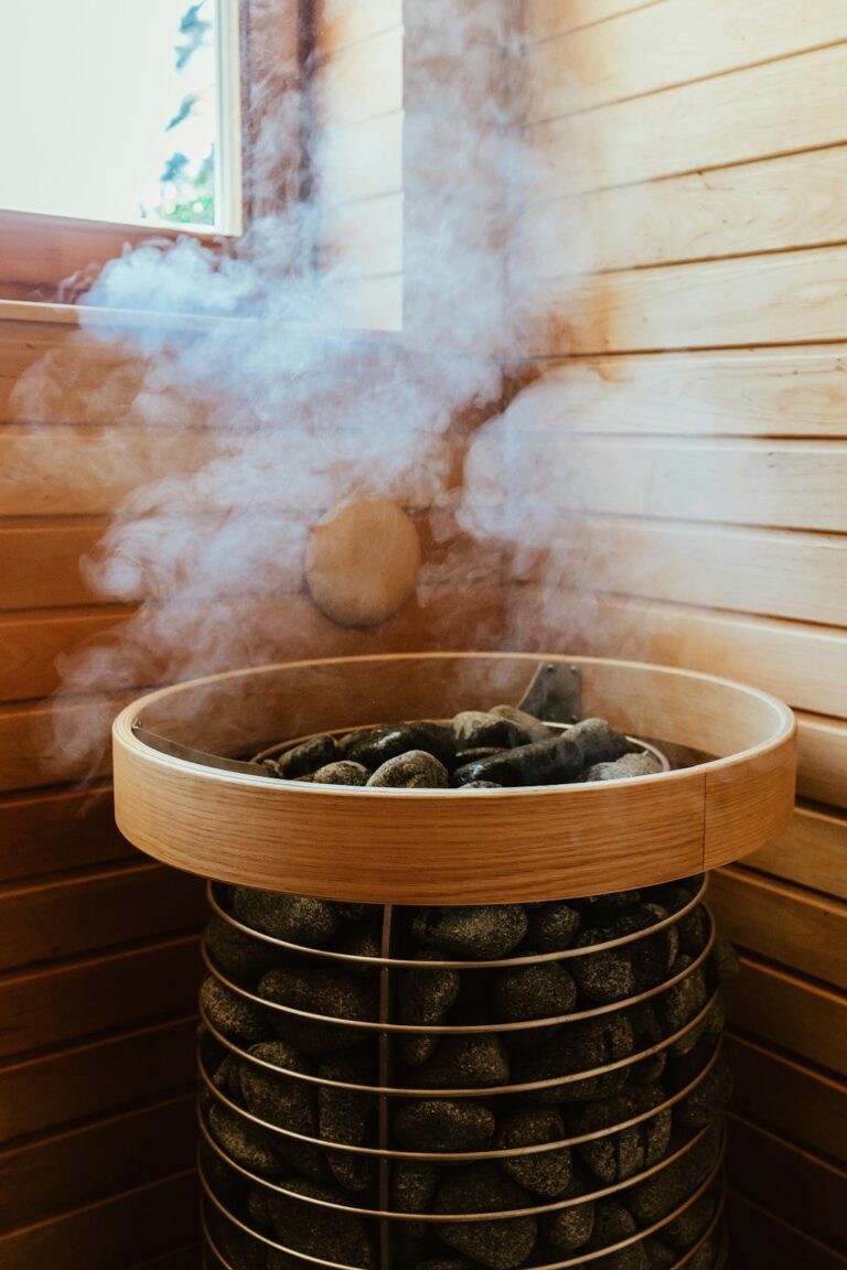 Steam rising from hot dark stones in a wooden sauna heater