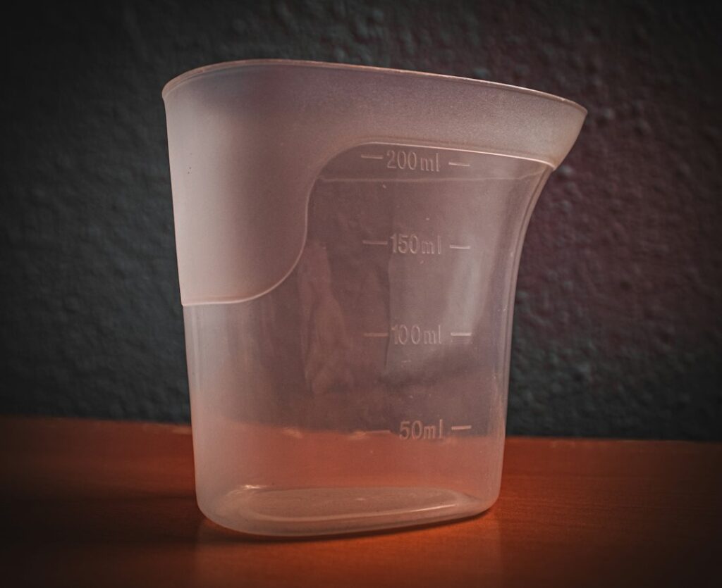 A plastic measuring cup sitting on top of a wooden table