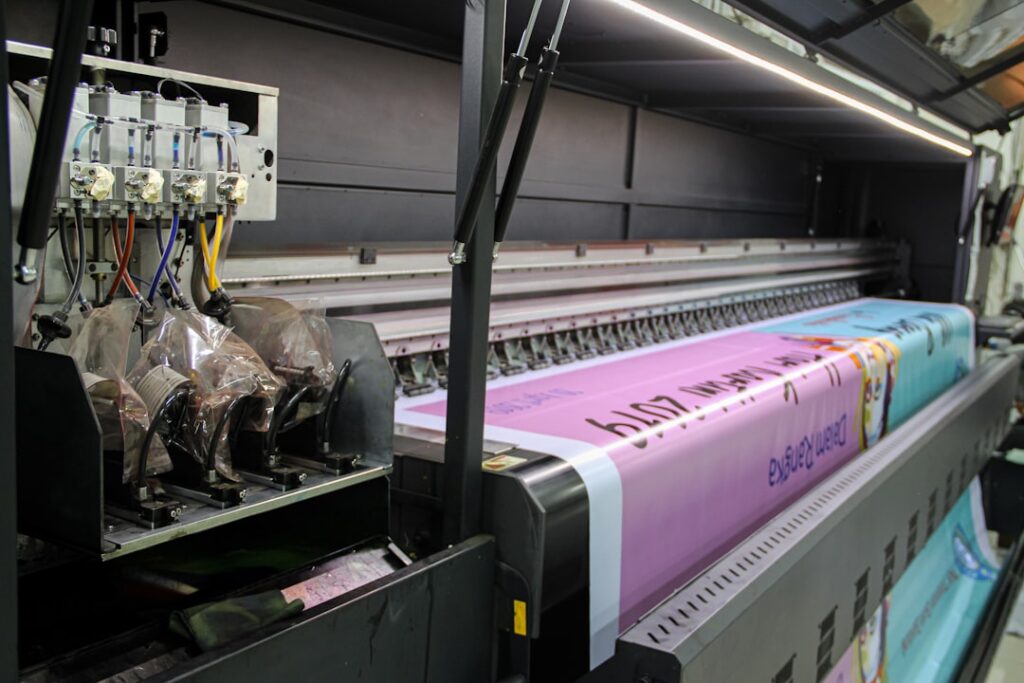 A large industrial printer feeding a long pink banner with printed text