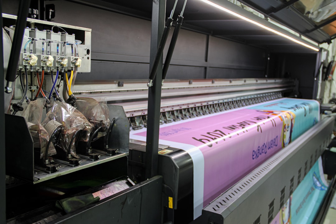 A large industrial printer feeding a long pink banner with printed text