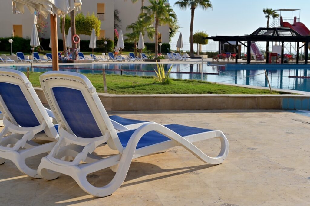 Lounge chairs sit by a pool on a sunny day